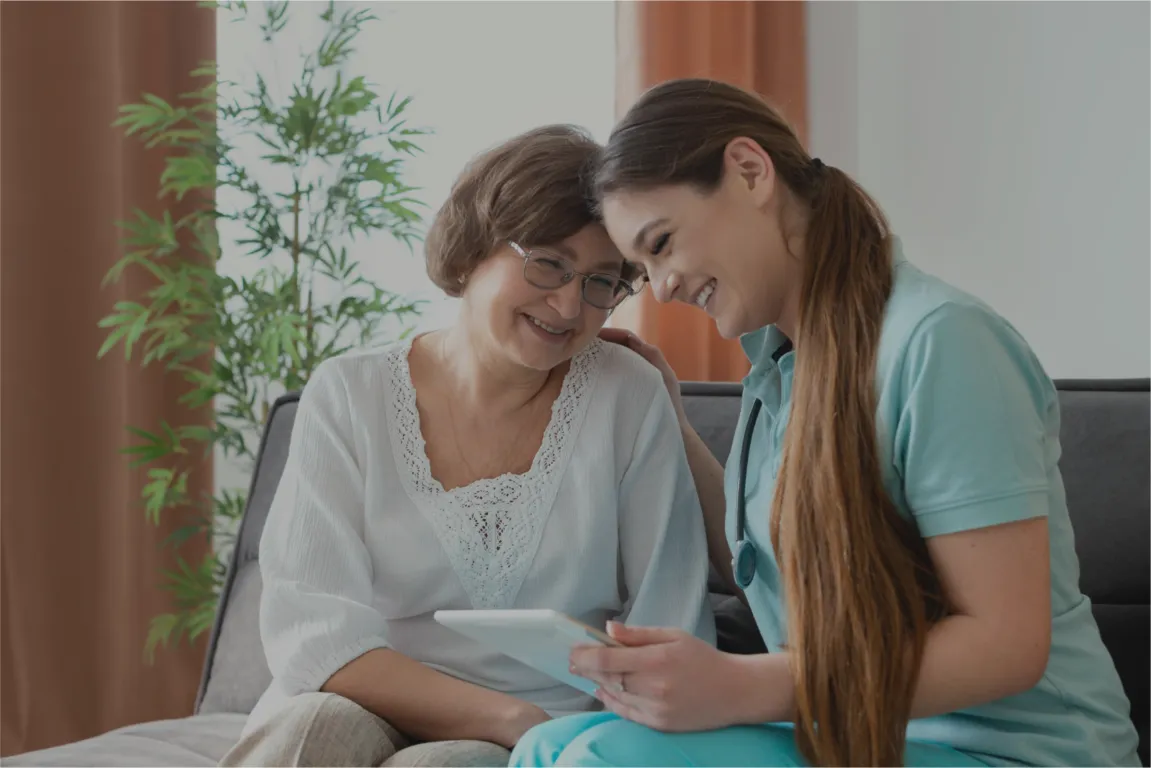 A Blisscare carer sharing a tablet and a laugh with an older woman